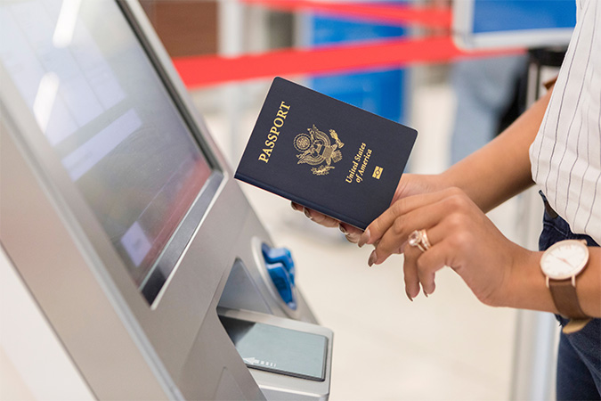 Person holding a passport standing by a machine.