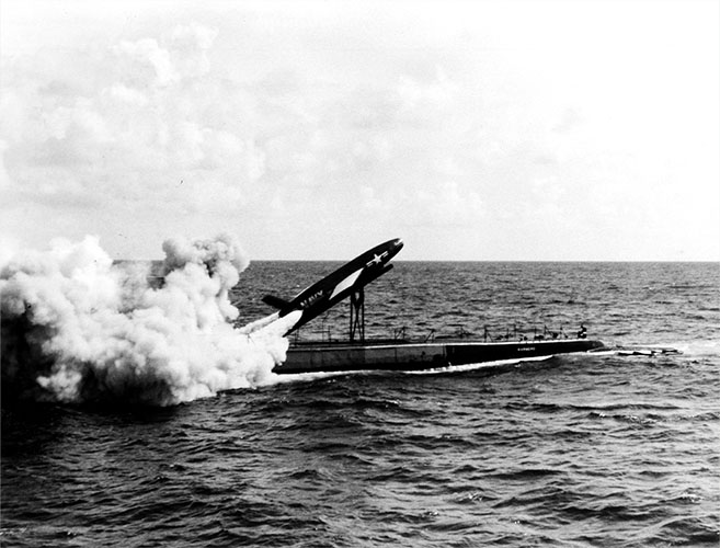 A black-and-white photograph of a missile launching from a submarine.