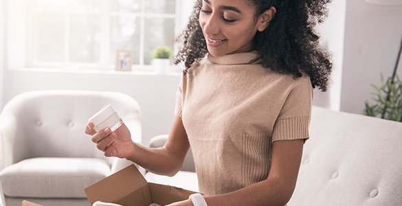 Joven retira un frasco de crema de muestra de un paquete de marketing mail.