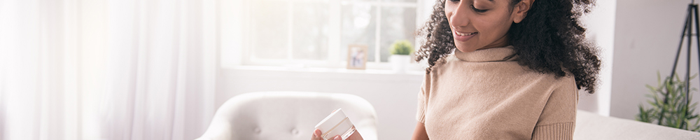 Young woman removes sample jar of cream from a marketing mail parcel.