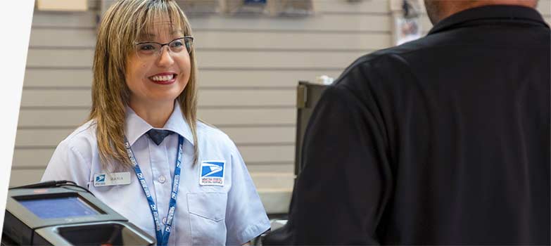 USPS retail associate selling products and services at the Post Office counter.