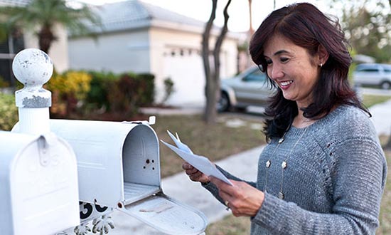 Una mujer leyendo las cartas que obtuvo de su buzón.