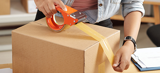 Un cliente colocando cinta en una caja para prepararla para el envío