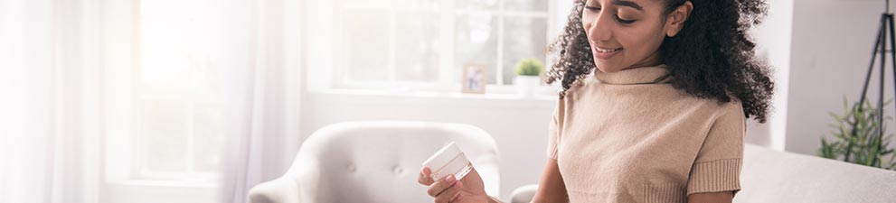 Young woman removes sample jar of cream from a marketing mail parcel.