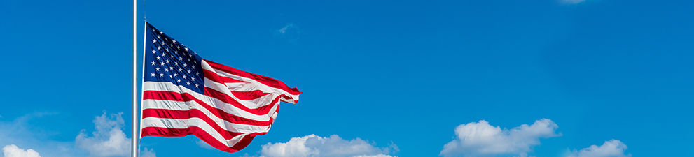An American flag at half-mast waving in the wind.