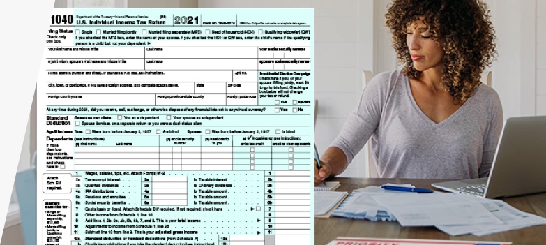 Woman doing taxes with computer, IRS form 1040, and USPS Priority Mail envelope.