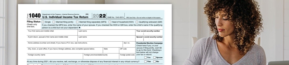 Woman doing taxes with computer, IRS form 1040, and USPS Priority Mail envelope.
