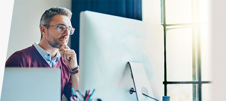 A man sitting at a computer looking at the computer screen.