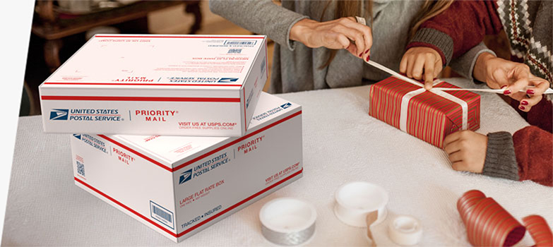 People wrapping holiday gifts they'll ship inside Priority Mail<sup>®</sup> boxes.
