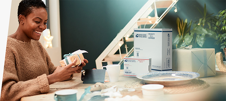 一位女士准备使用 Priority Mail Express 包装盒和 Priority Mail 包装盒寄送节日礼物。