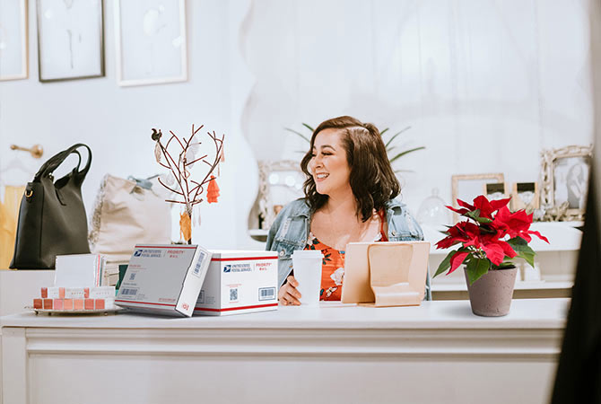 Female business owner at desk preparing to ship packages.