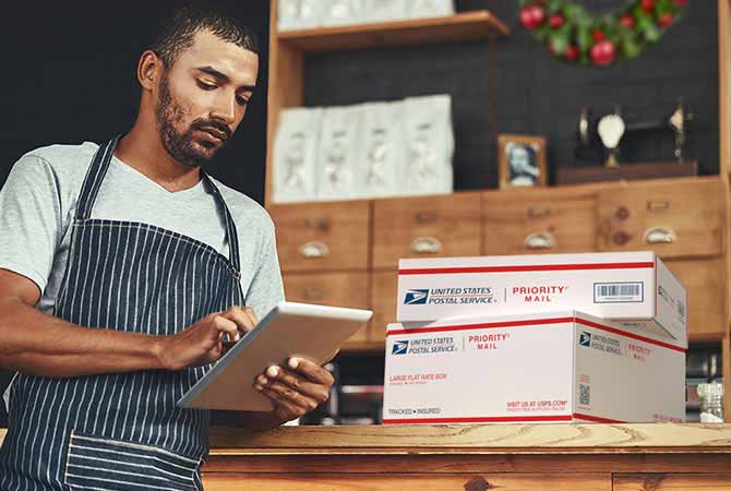 Man in striped apron preparing to ship packages.