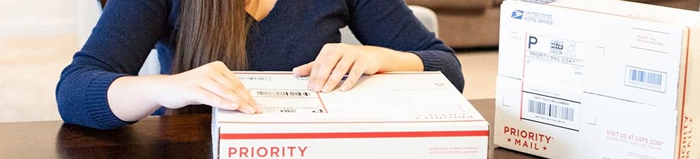 Mujer colocando una etiqueta de envío en una caja de Priority Mail.