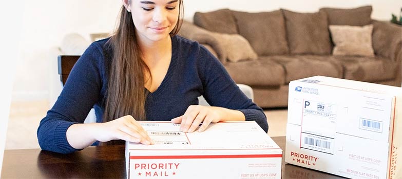 Mujer colocando una etiqueta de envío en una caja de Priority Mail.