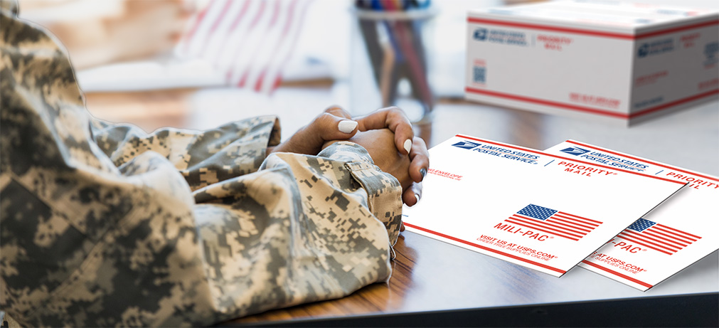 Military service member holding Priority Mail box.