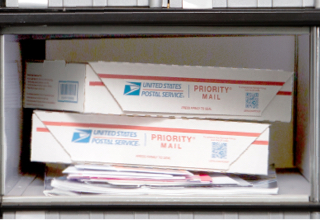 中型邮政信箱，3 号，小包裹堆放在杂志和大信封上。