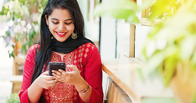 Una mujer sonriendo con un teléfono inteligente.