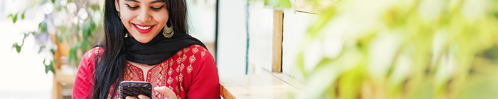 Una mujer sonriendo con un teléfono inteligente.