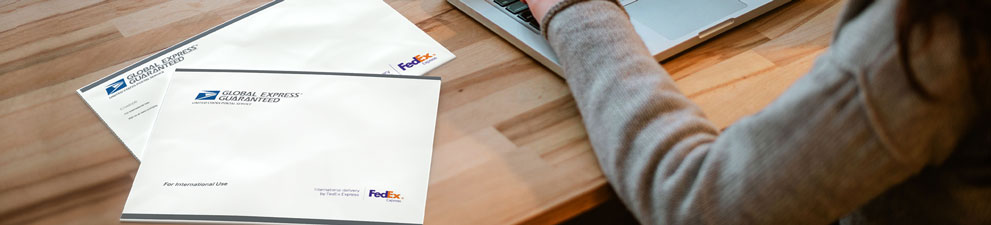 Two GXG® envelopes on a desk being prepared for sending.