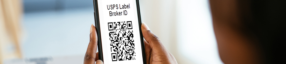 Person holding a smartphone showing a Label Broker ID (a QR Code) in front of a package.
