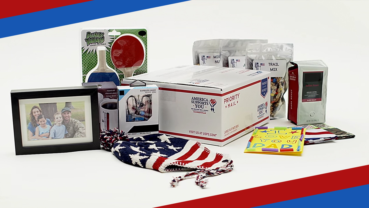  Una caja de Priority Mail rodeada de artículos que se pueden enviar en ella, incluida una foto familiar, un sombrero diseñado para parecerse a una bandera estadounidense, paletas, tarjetas de cumpleaños, mezcla de frutos secos, café y pequeños dispositivos electrónicos.