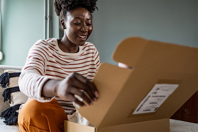 A person closing a shipping box with a label on it.
