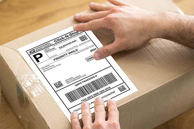 Person placing a label on a package.