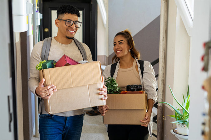 Two people carrying packing boxes while walking together.