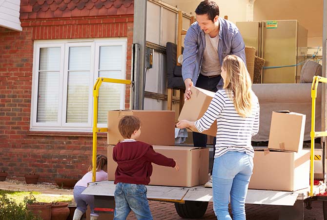 People happily carrying moving boxes to a new place.