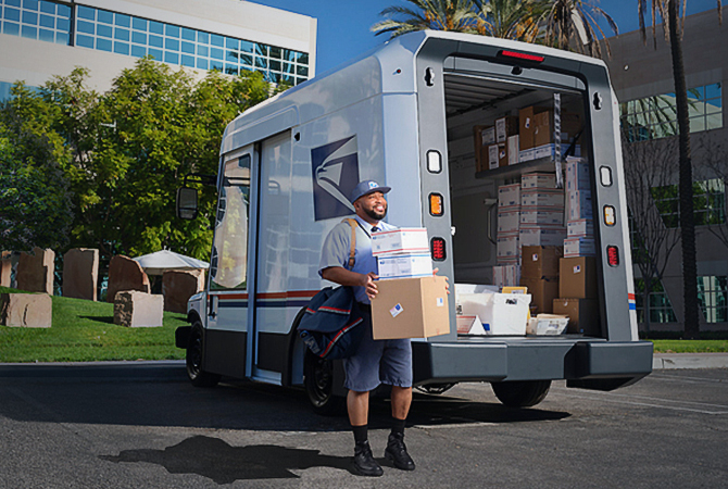准备递送从 USPS 下一代投递车后部卸下的包裹的信件承运人。
