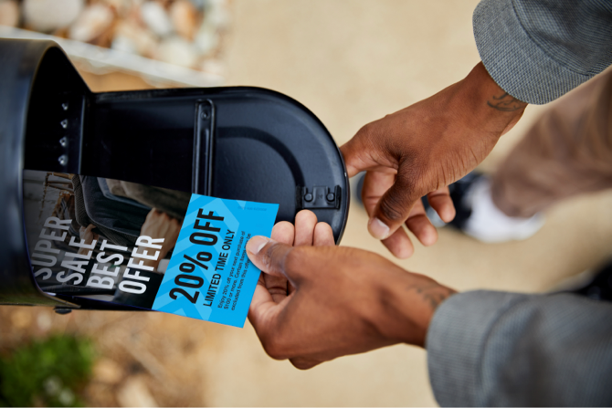 Marketing flyers being taken out of a mailbox by a person.