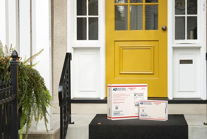 Priority Mail boxes on a house porch awaiting pickup.