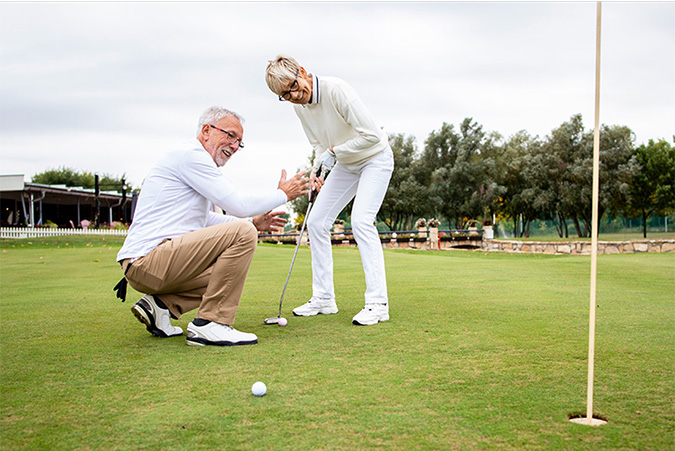 Two people enjoying themselves putting on a golf green.