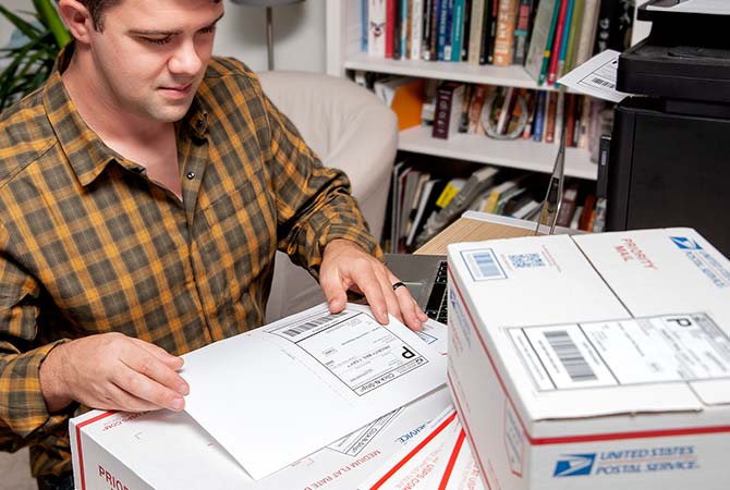 Business owner at a desk preparing to ship Priority Mail boxes.