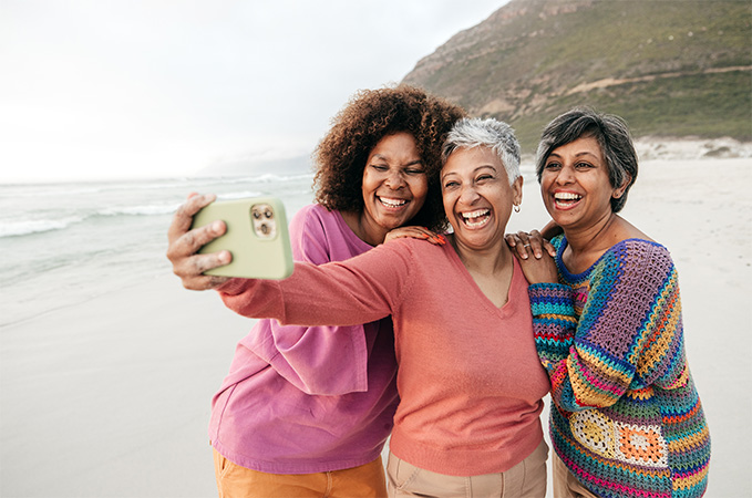 Three friends on a beach taking a photo.