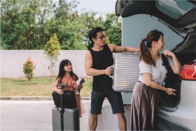 Una familia colocando equipaje en una camioneta.