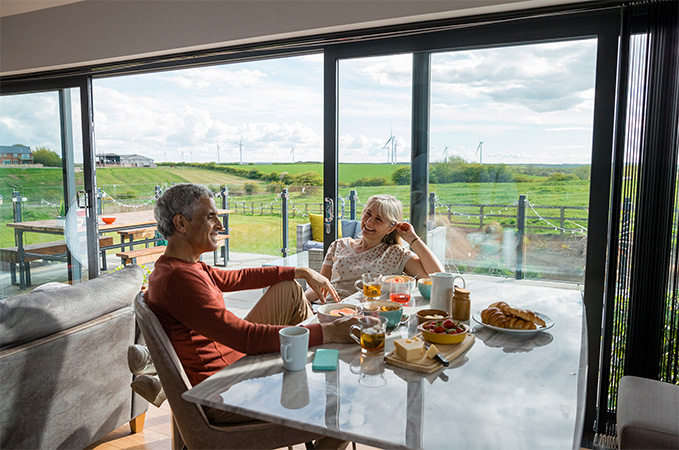 Two people enjoying themselves at a table with a large window behind them.