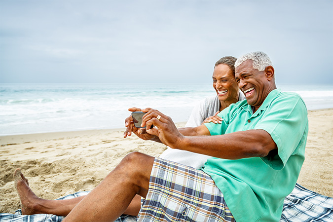 A couple taking selfies on a beach.