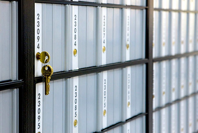 PO box with key in it on a wall of other PO Boxes.