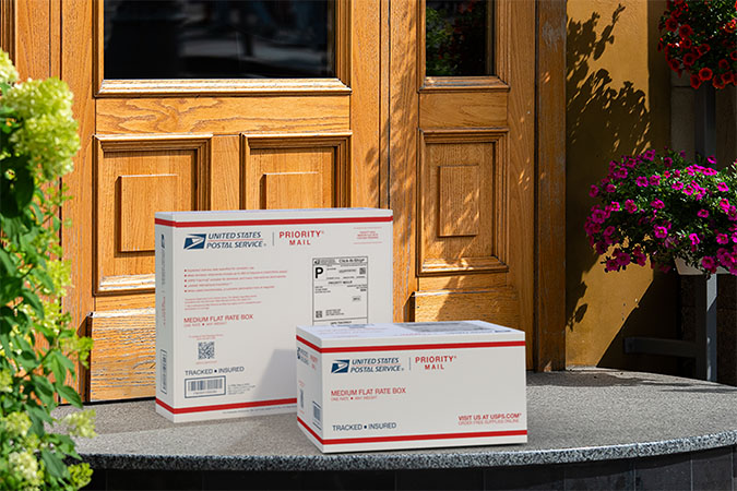 Priority Mail boxes on a house porch awaiting pickup.