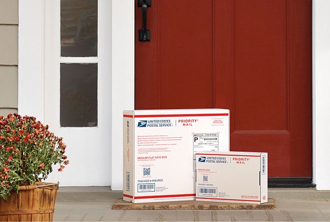 在房子门廊上等待取件的 Priority Mail 包装盒。
