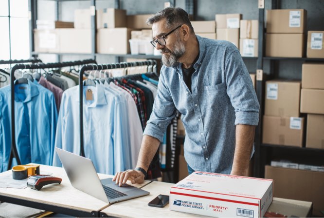 Small business owner on a laptop preparing to ship a Priority Mail box.