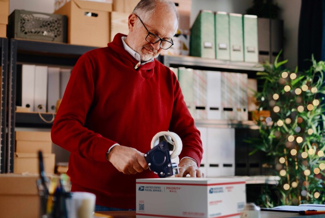 Small business owner taping a Priority Mail box.