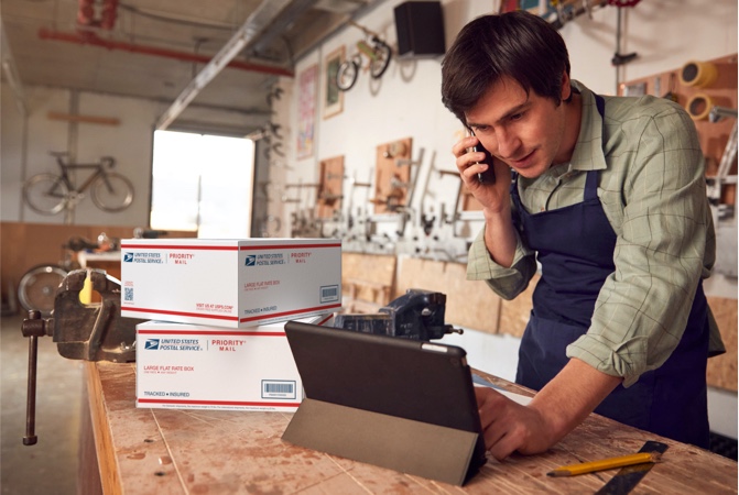 Propietario de negocio en un escritorio preparándose para realizar un envío usando cajas de Priority Mail.