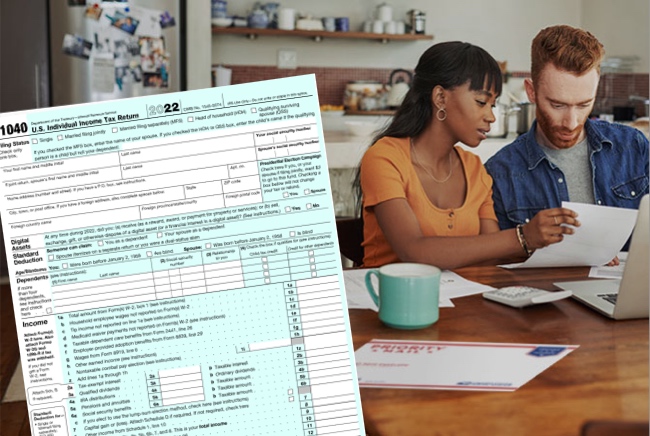 People doing taxes with laptop, IRS form 1040, and USPS Priority Mail envelope.
