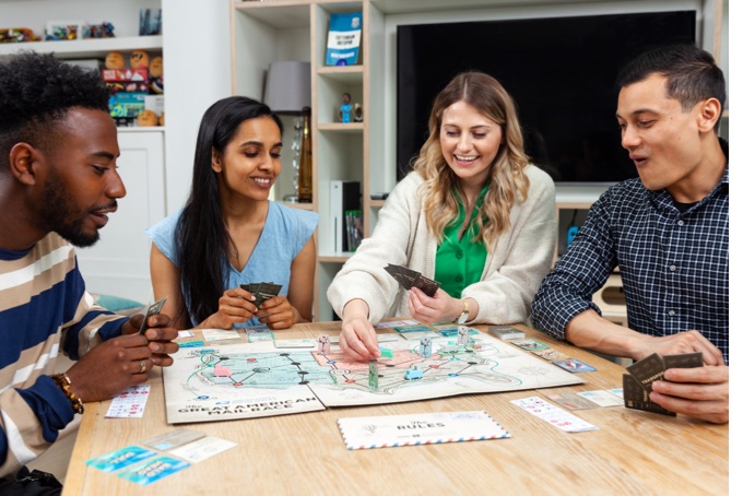 A group of people playing the family board game, USPS The Great American Mail Race.