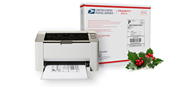 Priority Mail 包装盒旁打印机托盘中带有 CNS 寄件标签的打印机。