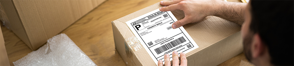 A person placing a label on a shipping box.