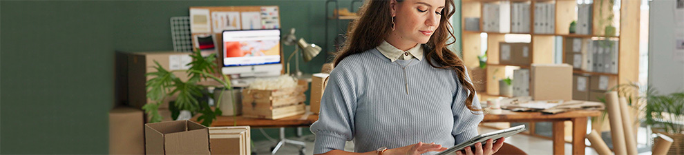 Woman on tablet preparing to ship packages.