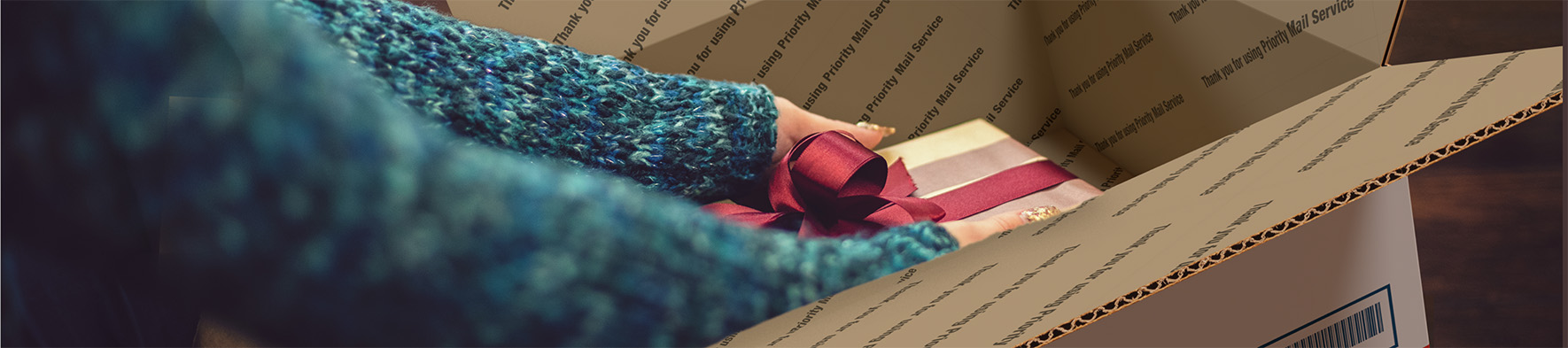 Person putting a gift in a Priority Mail box.